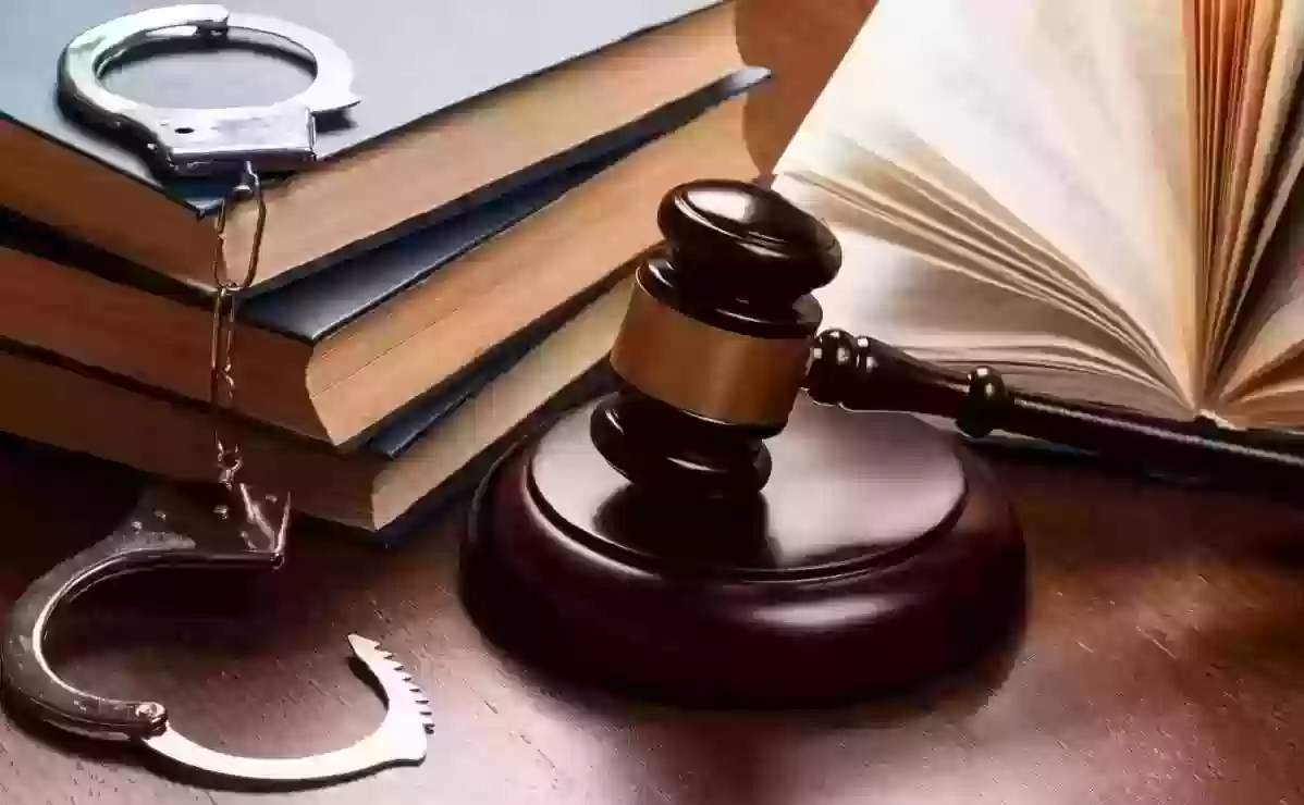cătușe, cărți de drept, un ciocan de judecător și o carte deschisă pe un birou de lemn
